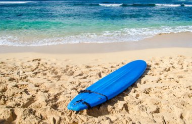 Surfboard on the sandy beach in Hawaii clipart