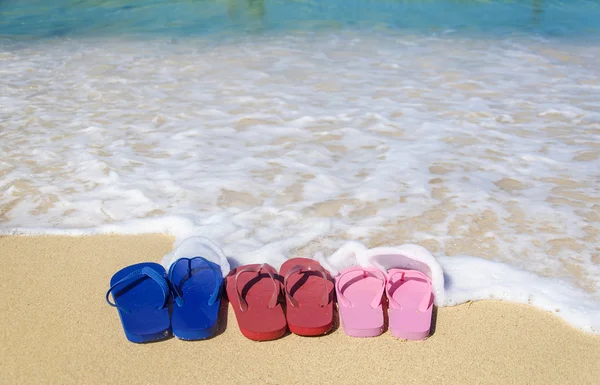 Tongs colorées sur la plage de sable — Photo