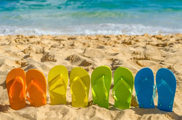 Tongs colorées sur la plage de sable — Photo