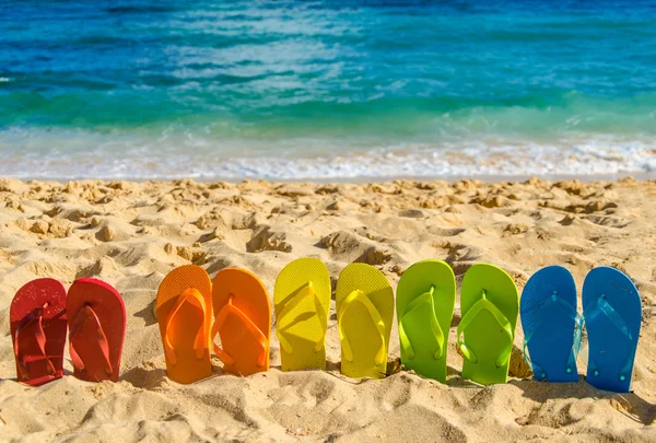 Kleurrijke flip flops op het zandstrand — Stockfoto