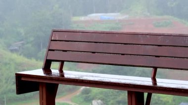 Parktaki hafif yağmurda boş ahşap bank. Beklenmedik bahar havası