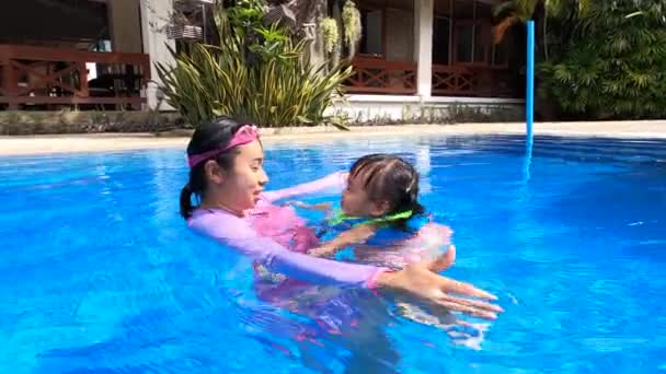炎热的夏天 快乐的年轻妈妈和她的女儿在游泳池里游泳 度假期间的家庭生活方式 — 图库视频影像