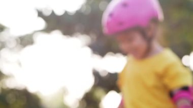 Anne, yaz parkında scooterını sürerken düştükten sonra kızını rahatlatıyor ve kucaklıyor. Çocuklar için aktif açık hava sporu.