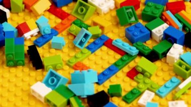 Sarı arka planda oyuncak renkli harflerle renkli oyuncak tuğlalar. Çocuklar için eğitici bir oyuncak.