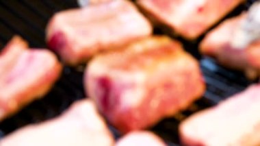 Yakın plan çekimde elinde maşayla domuz pirzolası pişirirken piknik sobasında küçük parçalar halinde kesilmiş..