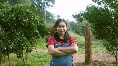Bir meyve bahçesinde taze organik portakallar, limonlar veya mandalinalarla kollarını kavuşturan dişi çiftçiler..