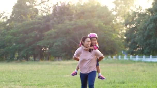一个可爱的小女儿和她的妈妈在夏天的公园里骑着小猪回来 她已经厌倦了骑摩托车 全家人都花时间在一起度假 — 图库视频影像