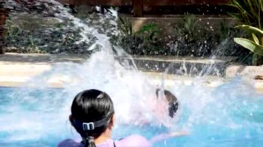 Mutlu küçük kız sıcak bir yaz gününde annesiyle havuzda yüzmeyi öğreniyor..