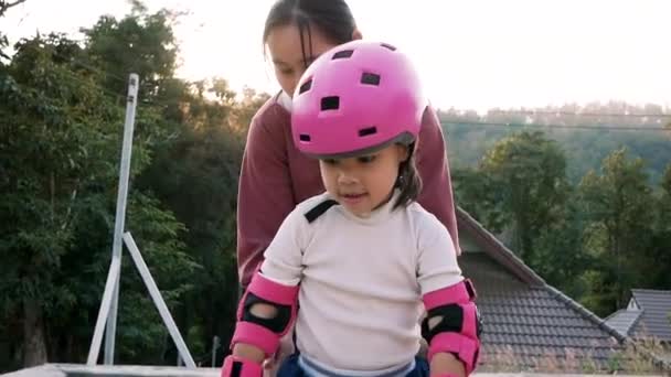 小女孩戴着防护垫和安全帽 在夏天的公园里和妈妈一起学习滑旱冰 积极为儿童提供户外运动 — 图库视频影像