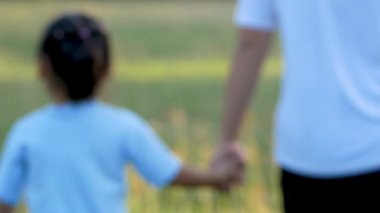 Mutlu anne ve kızı gün batımında bahçede el ele yürüyorlar. Aile ilişkileri kavramı.