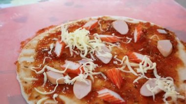 Küçük bir kızın pizza malzemesi, domates, sosis, yengeç çubuğu ve mozzarella peyniri ile pizza yaptığı yakın çekim. Ev yapımı pizza..