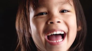 Kameraya bakıp evdeki stüdyoda gülümseyen şirin küçük bir kızın yakın plan yüz portresi. Mutlu bir çocukluk kavramı.