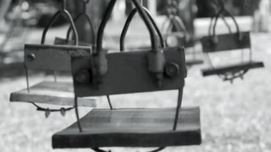 Yaz günü rüzgarla hareket eden çocukların oyun parkında boş salıncak. Siyah ve beyaz ton