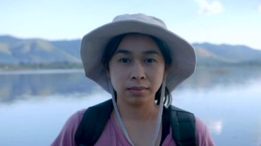 Genç bayan turistler güzel bir günbatımı gölü arka planında akıllı telefon kulaklığıyla müzik dinlerler. Yaşam tarzı ve Tatil kavramları.