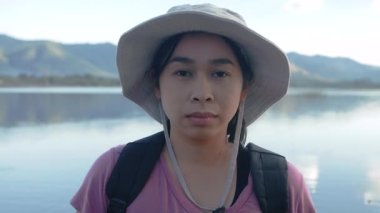 Genç bayan turistler güzel bir günbatımı gölü arka planında akıllı telefon kulaklığıyla müzik dinlerler. Yaşam tarzı ve Tatil kavramları.