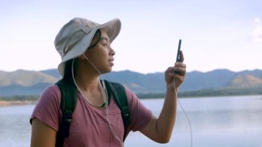 Genç bayan turistler güzel günbatımı gölü arka planında akıllı telefonlardan sohbet ediyorlar. Yaşam tarzı ve Tatil kavramları.