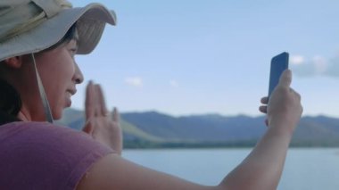 Genç bayan turistler güzel günbatımı gölü arka planında akıllı telefonlardan sohbet ediyorlar. Yaşam tarzı ve Tatil kavramları.