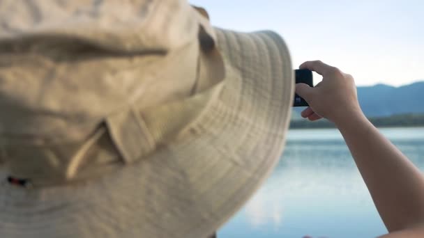 年轻的女性游客在日落时用智能手机拍照美丽的高山和湖泊 生活方式和假期概念 — 图库视频影像
