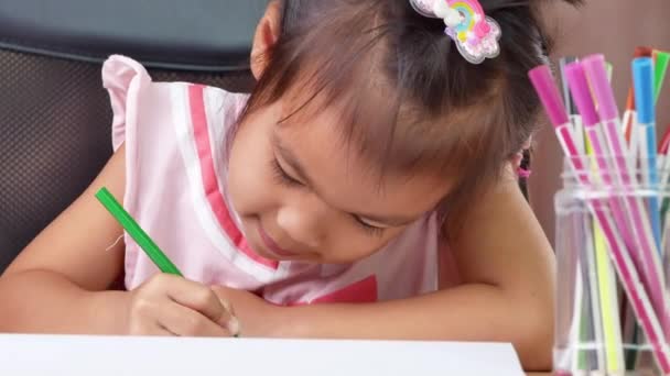 一个可爱的小女孩正在家里的桌上用彩色铅笔在纸上画彩虹 — 图库视频影像