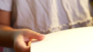 Kitap okuyan küçük tatlı bir kızın eli evde, masada oturuyor. Evde kalıp koronavirüs salgınından karantinaya alın. Ev okulu kavramı.