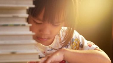 Kitap okuyan küçük tatlı bir kız evde masada oturuyor. Evde kalıp koronavirüs salgınından karantinaya alın. Ev okulu kavramı.