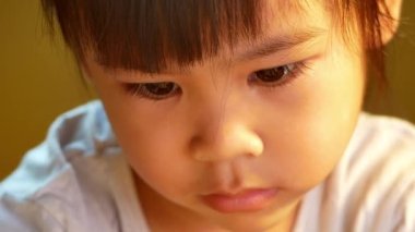 Kitap okuyan küçük tatlı bir kızın yakın plan yüzü evde masada oturuyor. Evde kalıp koronavirüs salgınından karantinaya alın. Ev okulu kavramı.