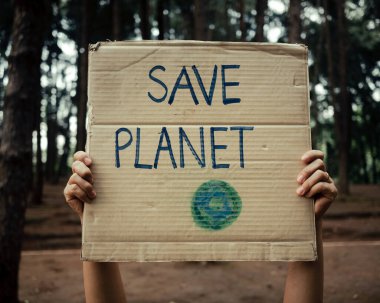 Dünya gezegenini kurtarmak için ormandaki kirliliği ve küresel ısınmayı protesto eden pankartlarla el ele tutuşmak. Dünya Çevre Günü kavramı.