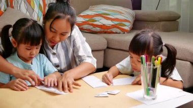 Anne ve çocuklar Japon kağıt katlama sanatını öğreniyorlar. Evde dekoratif şekiller ve figürler yapıyorlar..