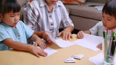 Anne ve çocuklar Japon kağıt katlama sanatını öğreniyorlar. Evde dekoratif şekiller ve figürler yapıyorlar..