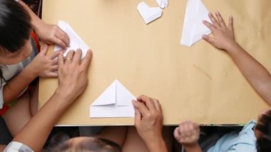 Anne ve çocukların eli Japon kağıt origamisini evde katlamayı öğreniyor. Kağıt katlama sanatı. Üst görünüm