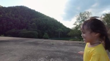 Yaz parkında oynayan mutlu küçük kız. Mutlu bir çocukluk. Gün batımında kız yol boyunca koşar.