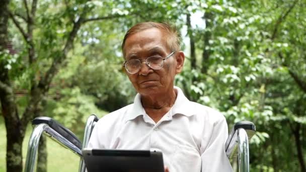 Senior Man Wheelchair Using Digital Tablet Looking Screen Reading Book — Stock Video