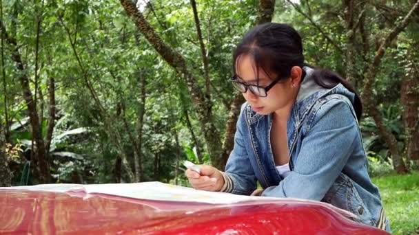 在国家公园的一次公路旅行中 妇女乘坐汽车去看地图 女性游客靠在汽车前盖上 在地图上寻找方向 — 图库视频影像