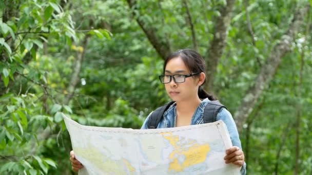 バックパック付きの女性観光客は 森の中で屋外をリラックスし マップ上で正しい方向を検索します 休暇のコンセプトで旅行とライフスタイル — ストック動画