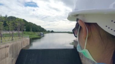 Koruyucu maske takan kadın mühendis baraj inşaatındaki su sistemini kontrol ediyor..