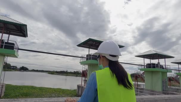 Kvinnlig Ingenjör Med Skyddsmask Och Skyddshjälm Kontrollerar Vattensystemet Vid Dammbygget — Stockvideo