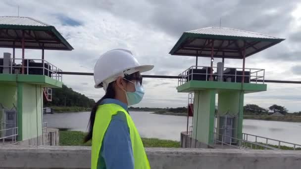 身穿防护面罩和安全帽的女工程师正在大坝建筑工地工作 以发电 — 图库视频影像