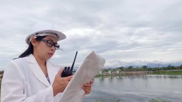 Женщина Инженер Белом Шлеме Считывает Данные Чертежу Использует Радиосвязь Строительной — стоковое видео