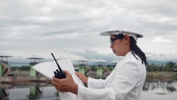 Женщина Инженер Белом Шлеме Использующая Радиосвязь Рабочим Строительной Площадке Плотины — стоковое видео