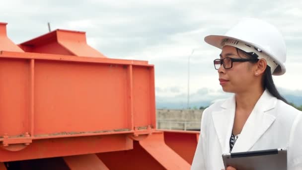在大坝建筑工地 戴着白色头盔的女工程师手持数字平板电脑和检查设备发电 — 图库视频影像
