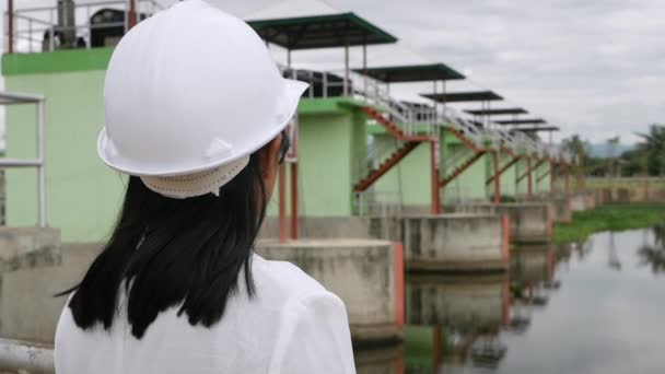戴白色头盔的女工程师正在使用数字平板电脑 看着大坝建筑工地以外的地方发电 — 图库视频影像