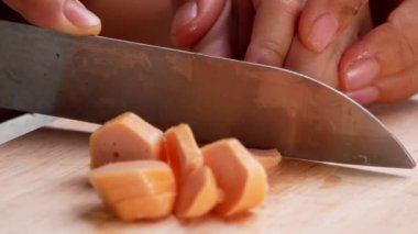 Bıçağın ucu sosisi küçük parçalara ayırır. Anne, evde spagetti yerken Borona sosu yapmak için sosis kesmeyi öğretmek için kızının elini tutuyor..