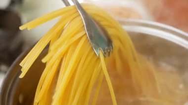 Çiğ spagetti, mutfak kabında kaynar suda pişiriliyor. Sağlıklı İtalyan Yemek ve Pişirme kavramları.