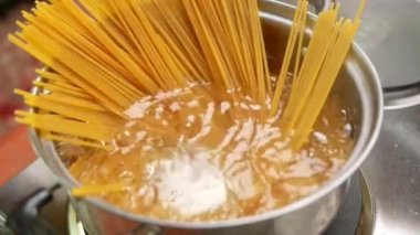Çiğ spagetti, mutfak kabında kaynar suda pişiriliyor. Sağlıklı İtalyan Yemek ve Pişirme kavramları.
