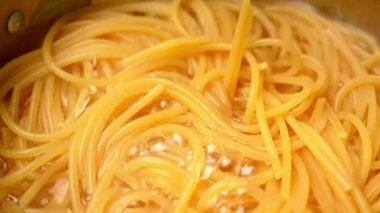 Çiğ spagetti, mutfak kabında kaynar suda pişiriliyor. Sağlıklı İtalyan Yemek ve Pişirme kavramları.