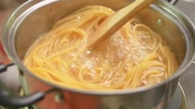 Çiğ spagetti, mutfak kabında kaynar suda pişiriliyor. Sağlıklı İtalyan Yemek ve Pişirme kavramları.