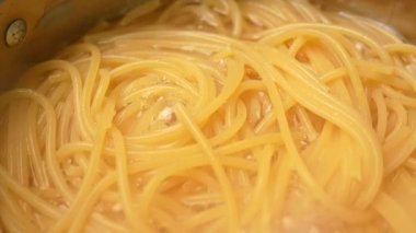 Çiğ spagetti, mutfak kabında kaynar suda pişiriliyor. Sağlıklı İtalyan Yemek ve Pişirme kavramları.
