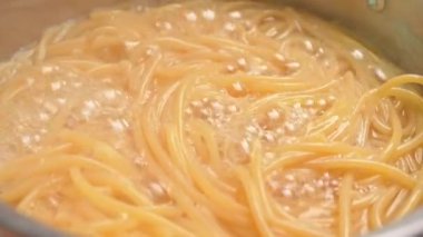 Çiğ spagetti, mutfak kabında kaynar suda pişiriliyor. Sağlıklı İtalyan Yemek ve Pişirme kavramları.