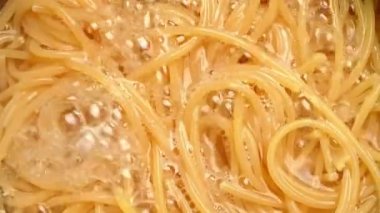 Çiğ spagetti, mutfak kabında kaynar suda pişiriliyor. Sağlıklı İtalyan Yemek ve Pişirme kavramları.