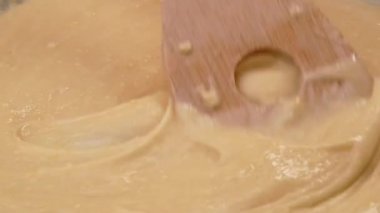 Un, taze süt ve tavuk yumurtalarını spatulayla karıştıran kadın eller kahvaltı için ev yapımı krep hazırlar. Yemek pişirme süreci. Krep tarifi.